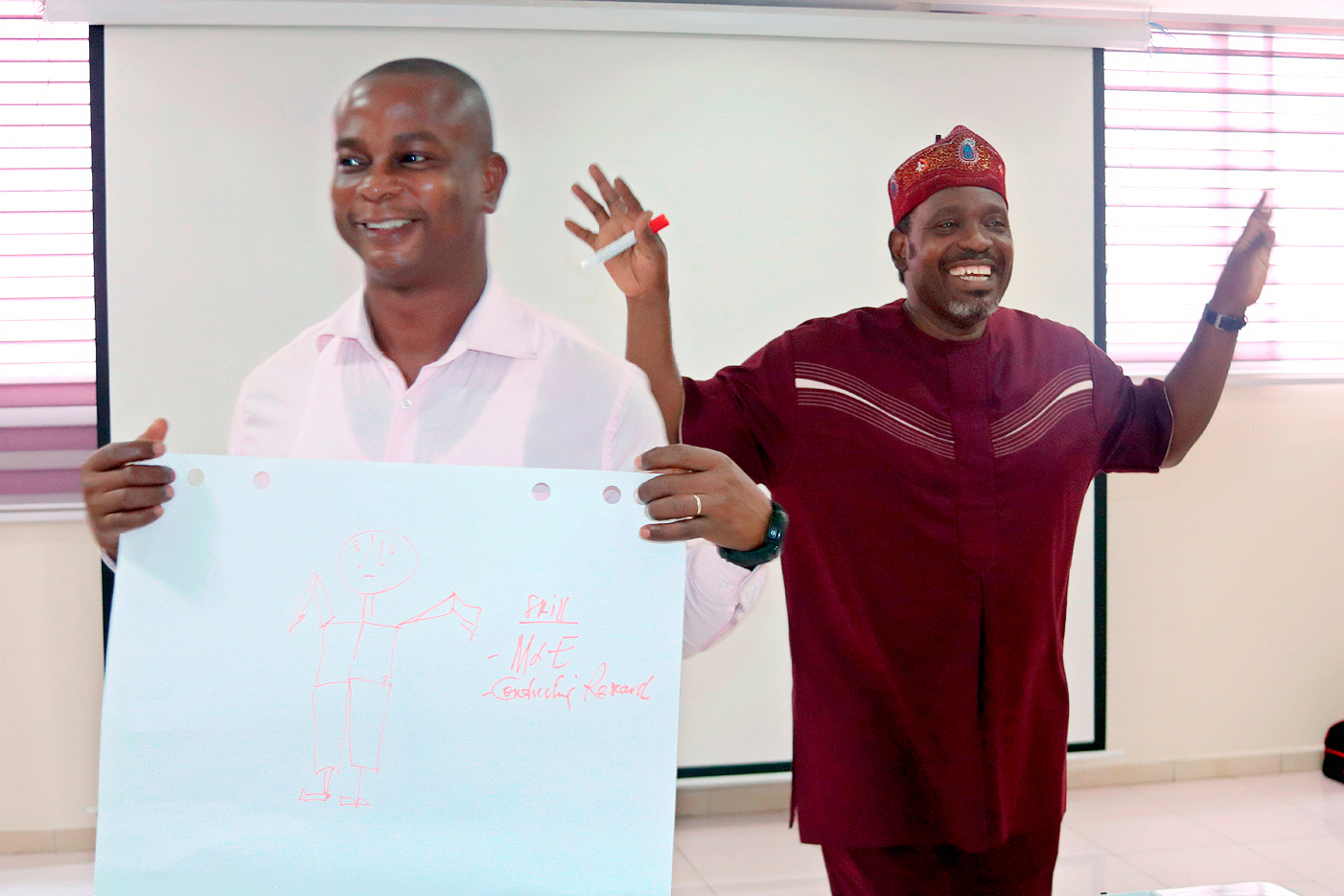 two male presenters at Ghana workshop, one holding flipchart